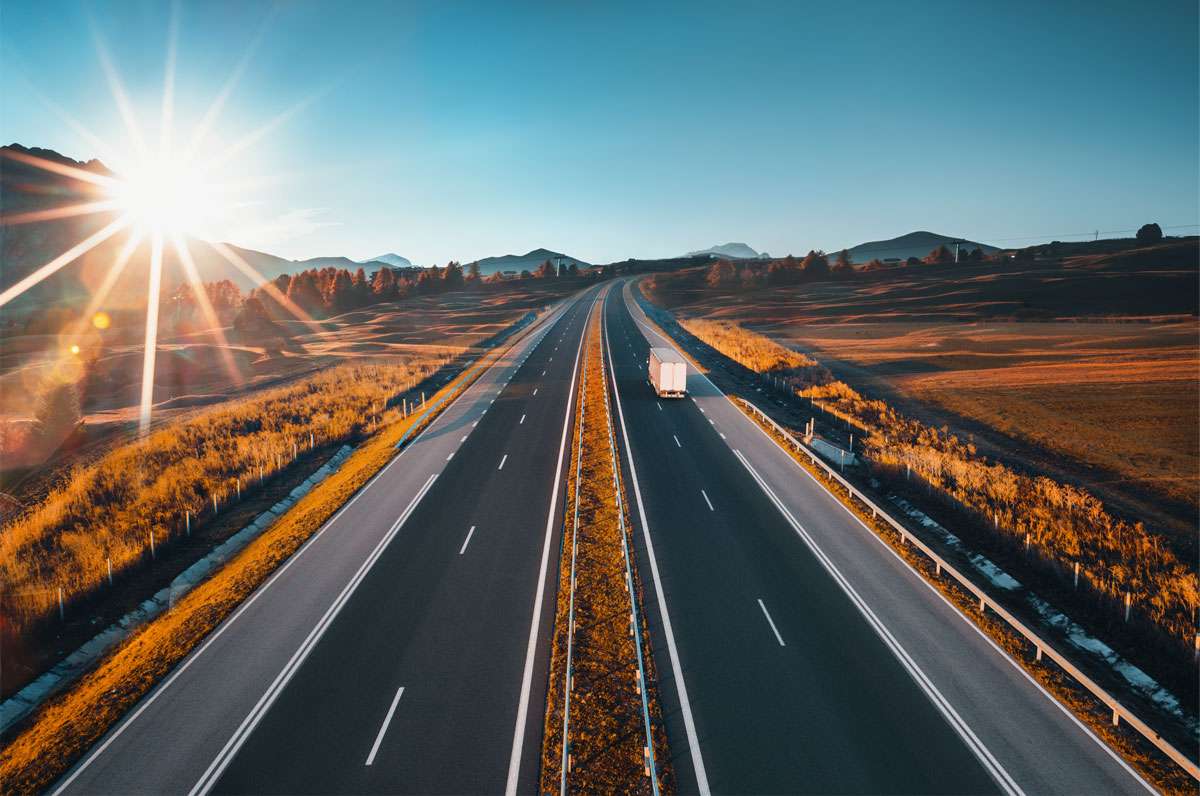 A lone truck drives by two highways in a gorgeous stretch.